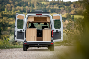 camping-car-portes-ouvertes-interieur-cosy-paysage-verdoyant